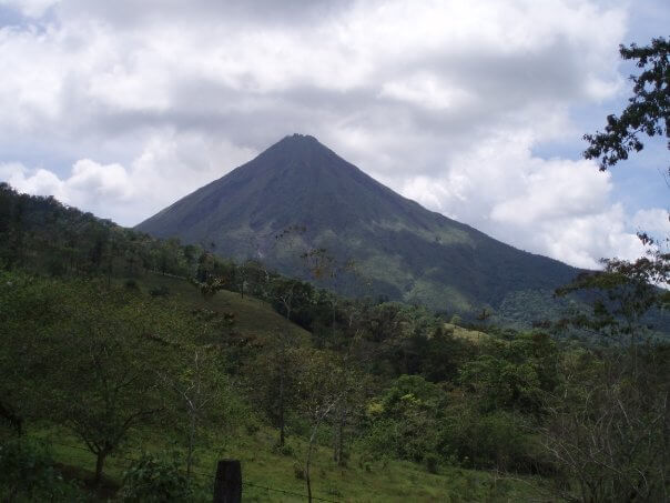 A view of a hillside with the Arenal Volcano behind it, in Costa Rica.