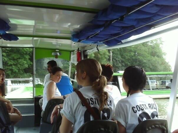 The backs of myself and a friend, wearing 'Costa Rica 08' t-shirts, sitting on a boat during a tour of the Sarapiqui River in Costa Rica.