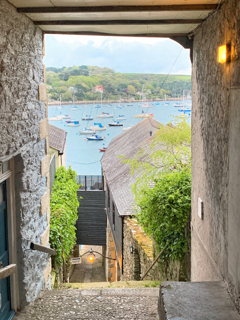 A view through a stone archway in Falmouth looking out across lots of small fishing boats bobbing on the water.