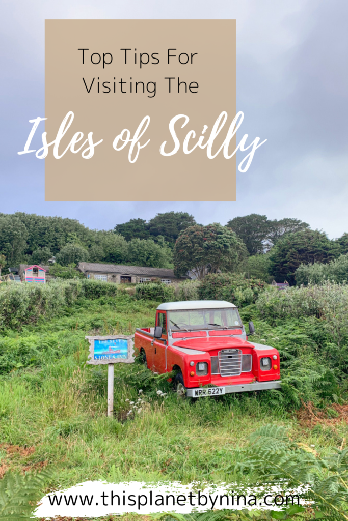 An old red truck sits in the middle of an overgrown field, with a blue sign to its left that says "The Seven Stones Inn". Blog post - Top Tips for the Isles of Scilly.