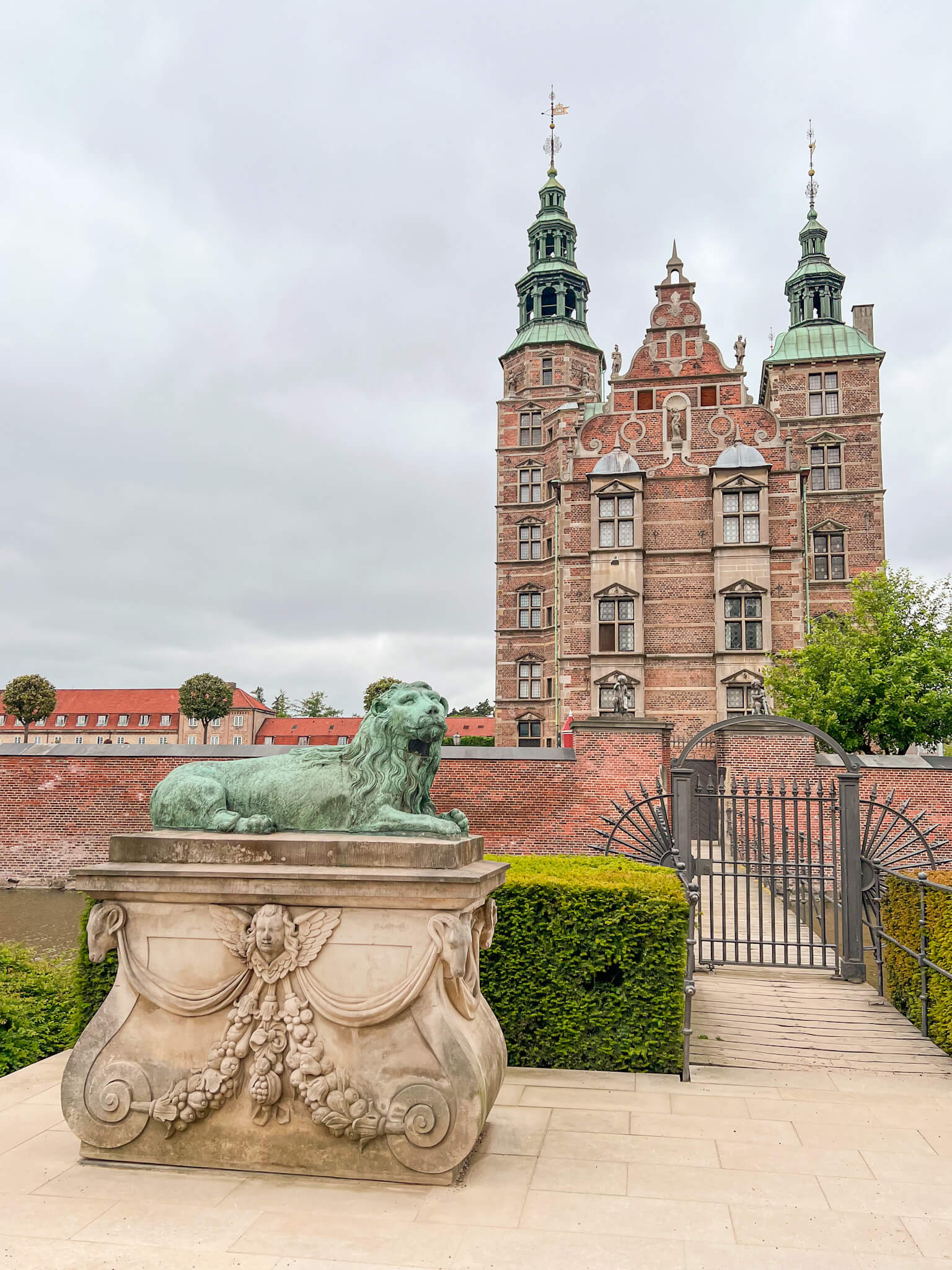 A front view of Rosenborg Castle with green lion statue guarding the iron gate. One of my top 10 places to visit in Copenhagen.