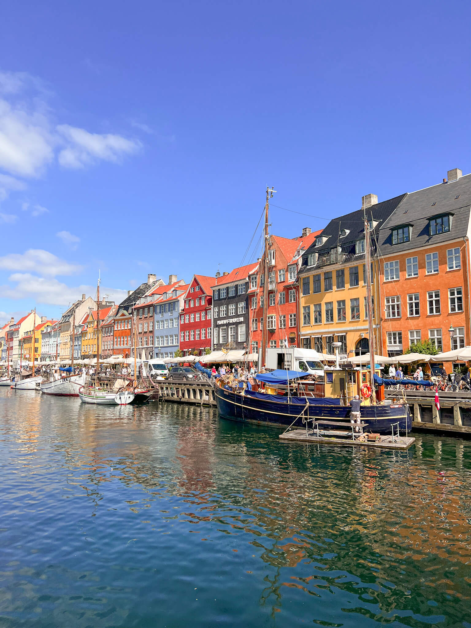 View across the canal of the wooden boats and colourful buildings of Nyhavn. One of my top 10 places to visit in Copenhagen.