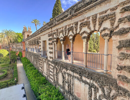 Nina stands in the distance under the arches on the wall in the gardens of the Real Alcazar de Sevilla - 10 things to do in Seville