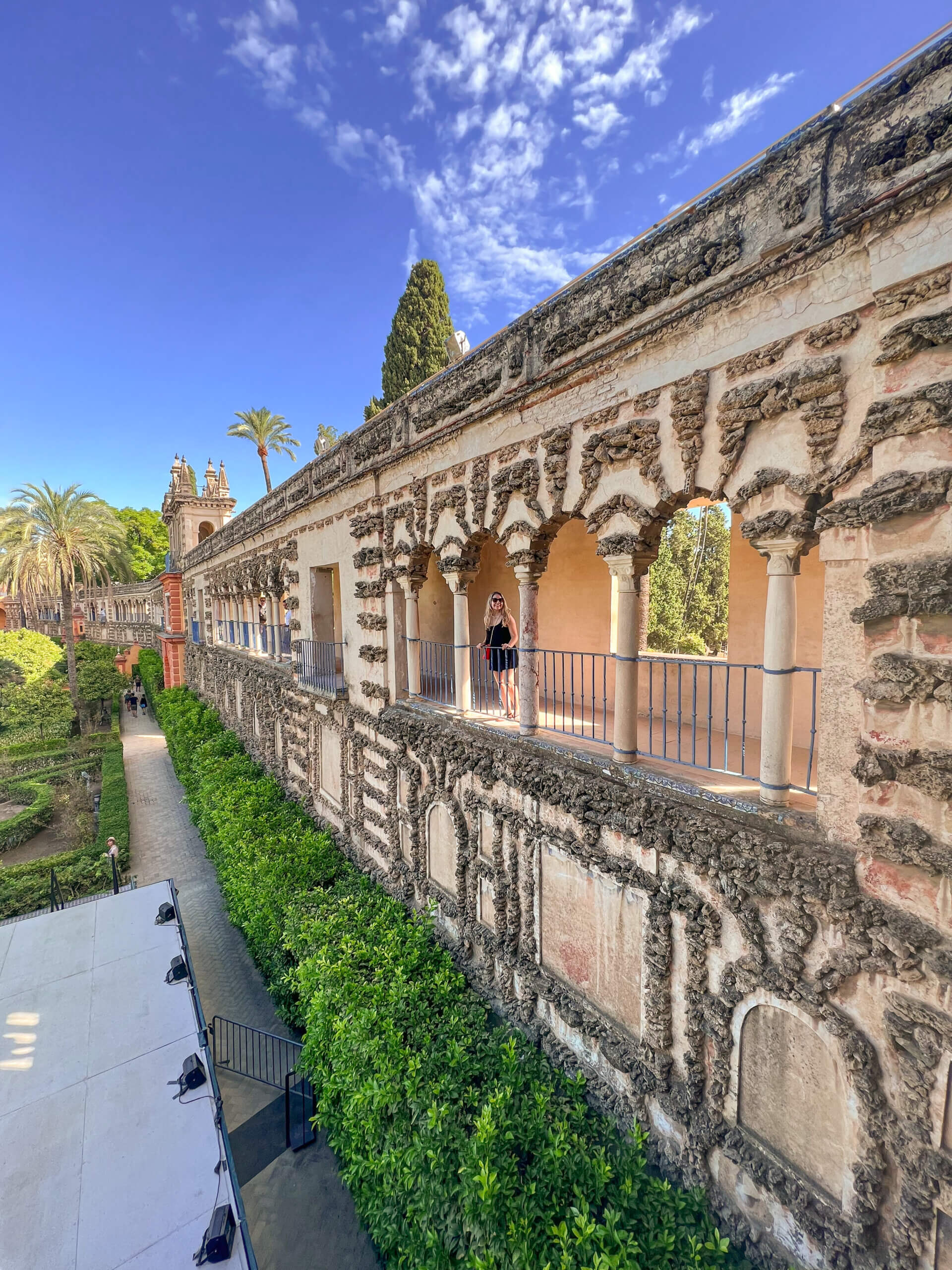 Nina stands in the distance under the arches on the wall in the gardens of the Real Alcazar de Sevilla - 10 things to do in Seville