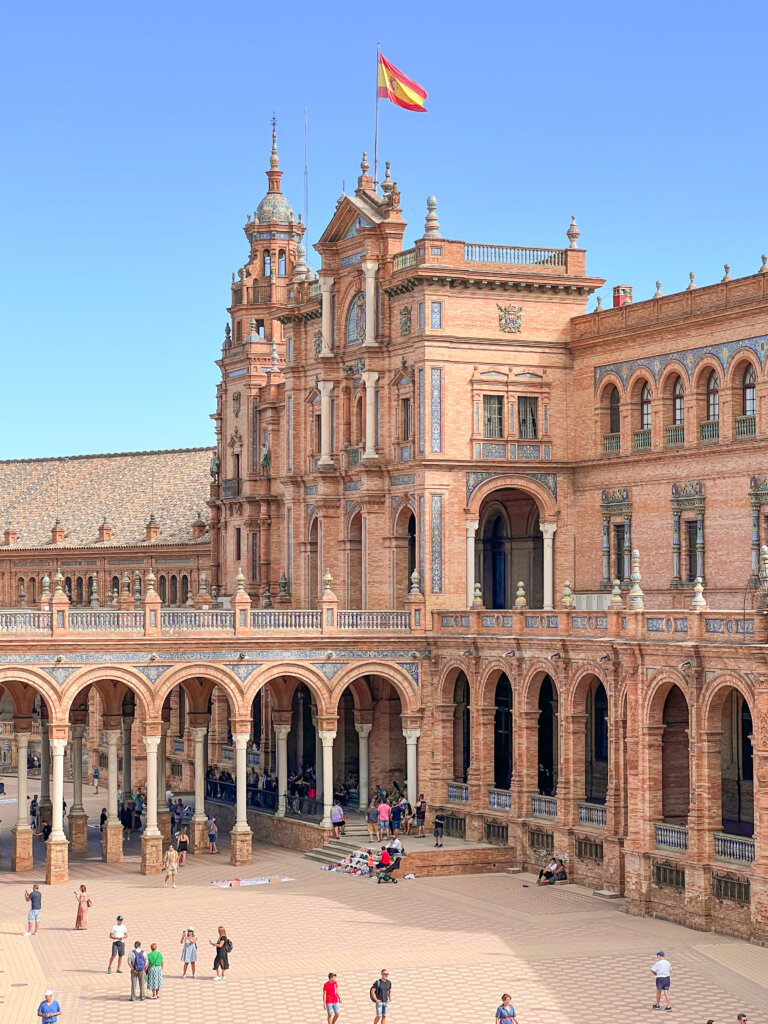 View of the building at La Plaza de España with the Spanish flag on top - 10 things to do in Seville.