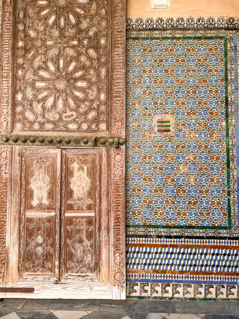 Decorative big wooden door on the left and intricate mosaic tiled wall on the right - 10 things to do in Seville.